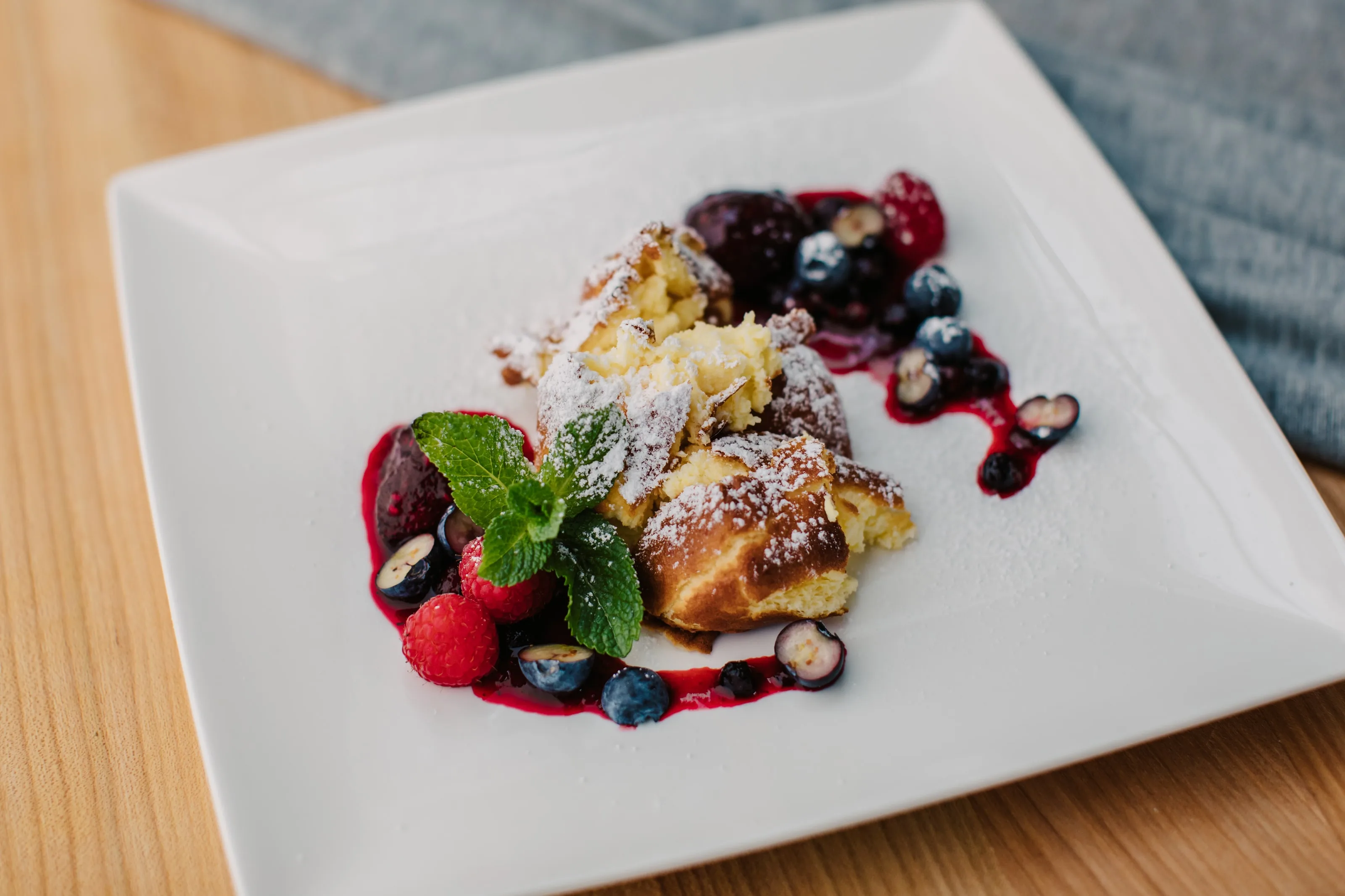 Rahmschmarrn mit Staubzucker, Beerenröster, frischen Beeren und Minze