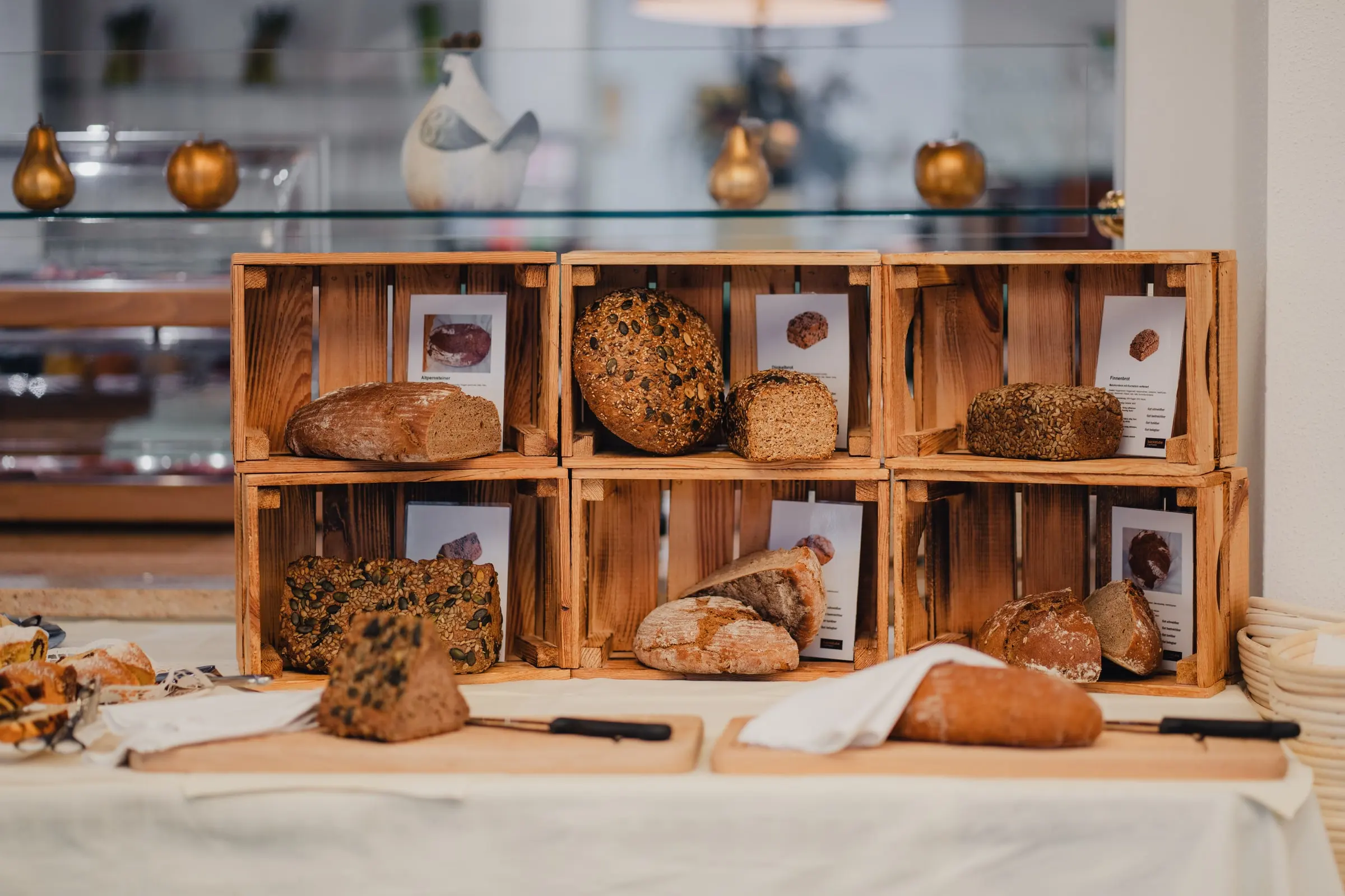 Holzkisten mit verschiedenen Broten am Frühstücksbuffet, davor Schneidbretter
