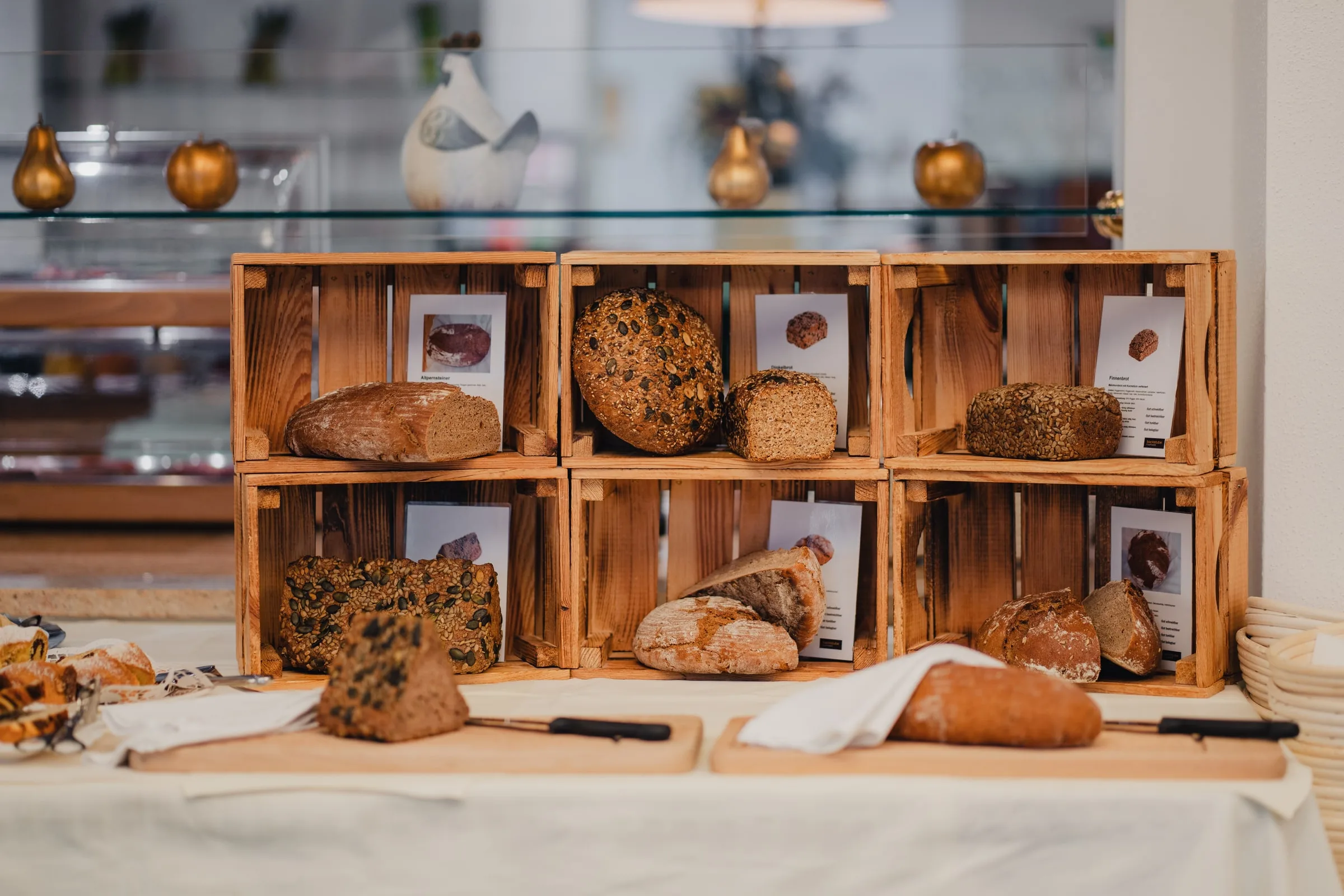 Holzkisten mit verschiedenen Broten am Frühstücksbuffet, davor Schneidbretter
