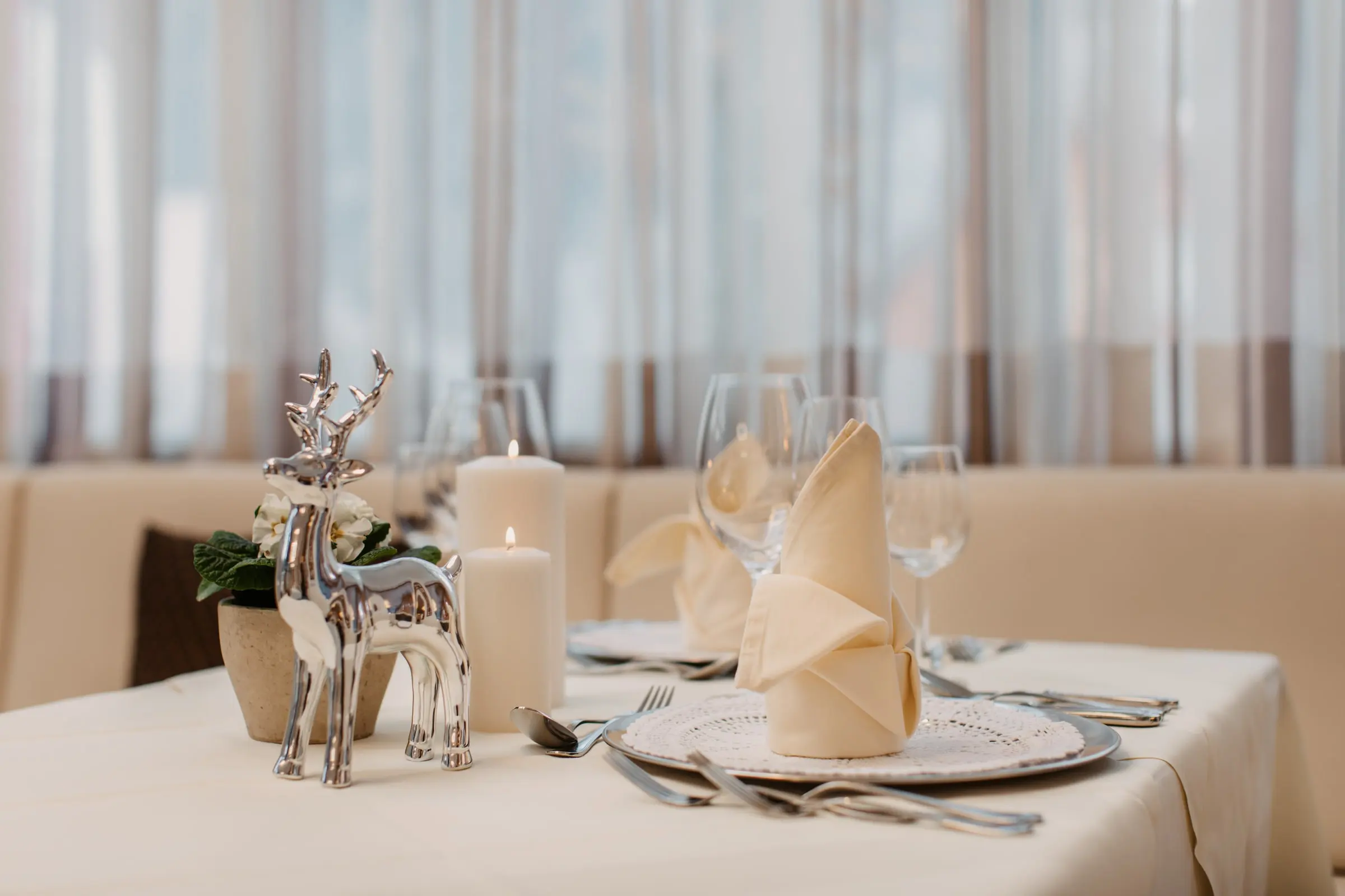 Festlich gedeckter Tisch mit Kerzen, gefalteter Serviette und silberner Hirschfigur
