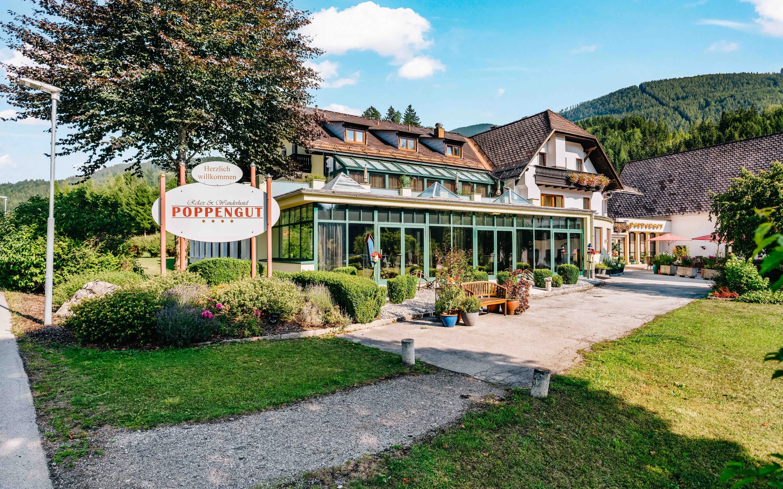 Die Einfahrt zum Poppengut mit dem Hotelschild und dem Wintergarten