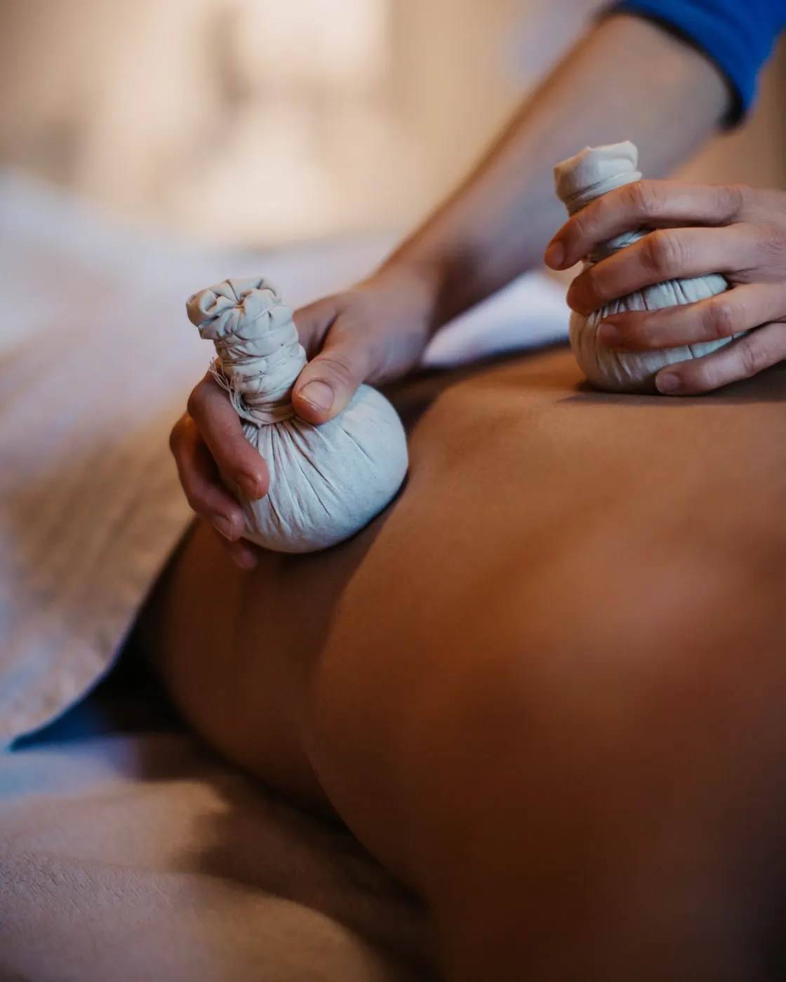 © Selina Flasch Photography Detail masáže bylinnými tampony: ruka přitlačuje bylinný tampon na nahá záda