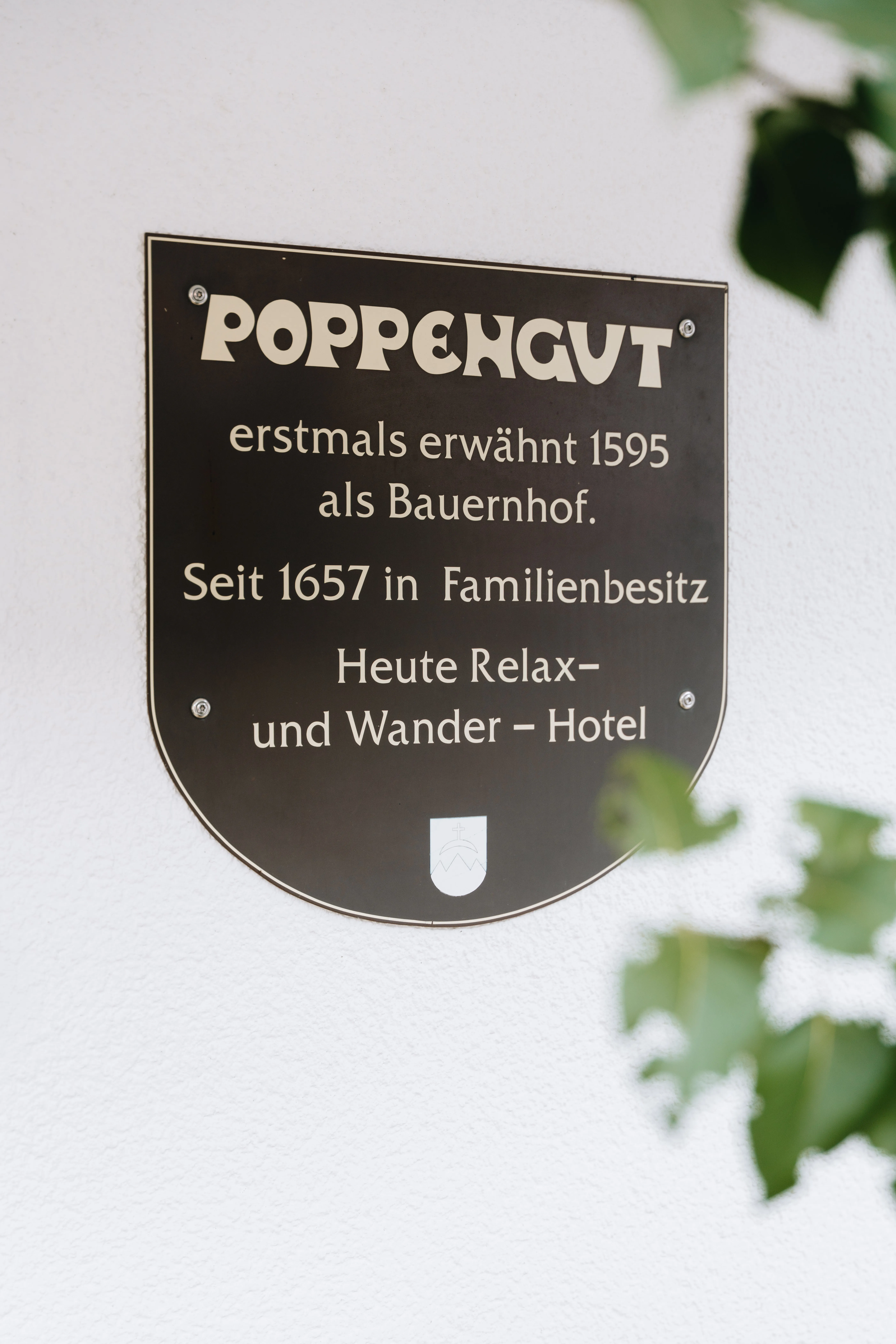 © Hartwig Winkler Štít s erbem na zdi domu — Poppengut, první zmínka z roku 1595 jako statek, od roku 1657 v rodinném majetku, dnes Relax- & Wanderhotel