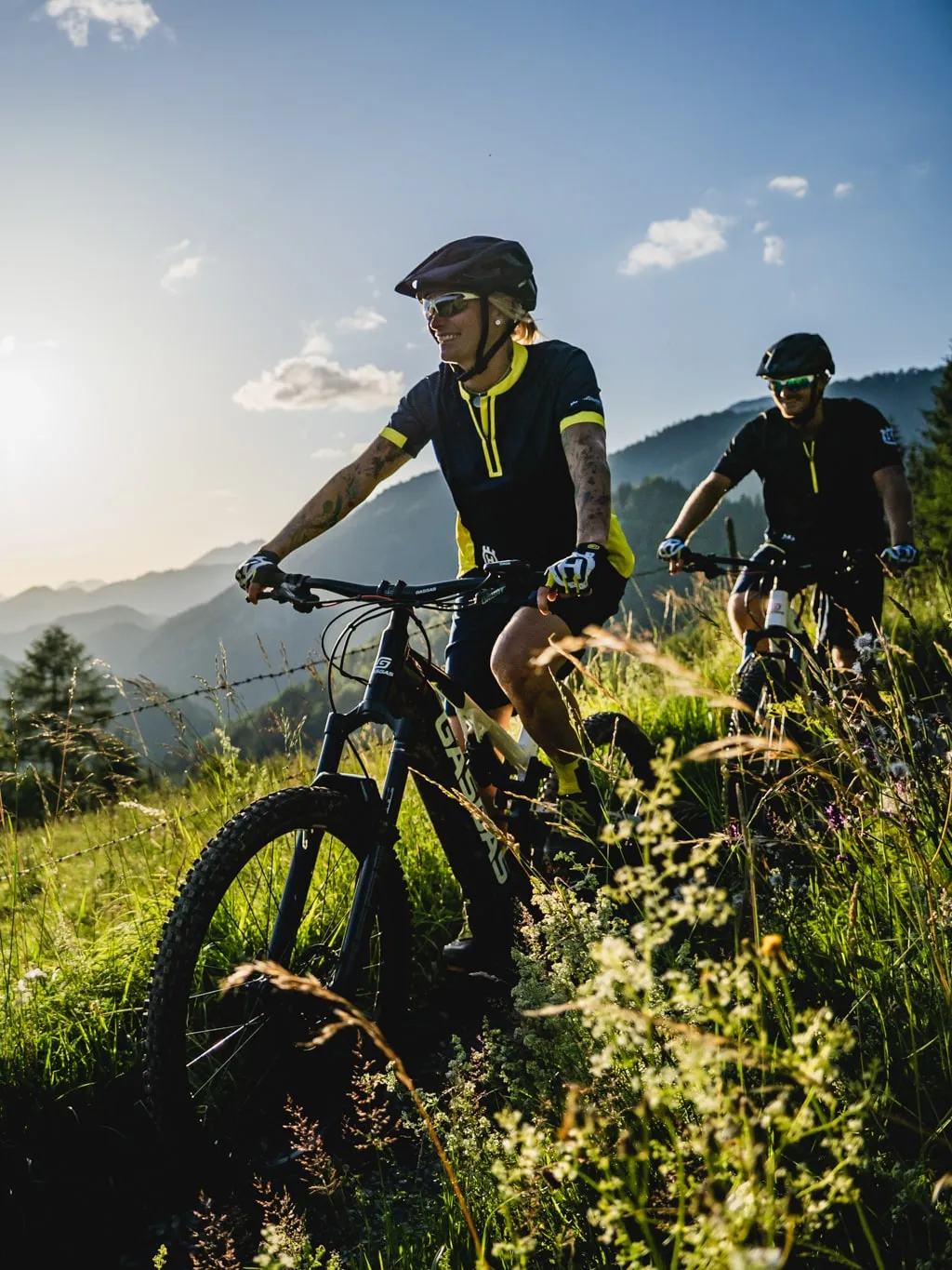 © Markus Kohlmayr / Pyhrn-Priel Tourismus GmbH Dva cyklisté na elektrických horských kolech na horské louce ve večerním světle, region Pyhrn-Priel