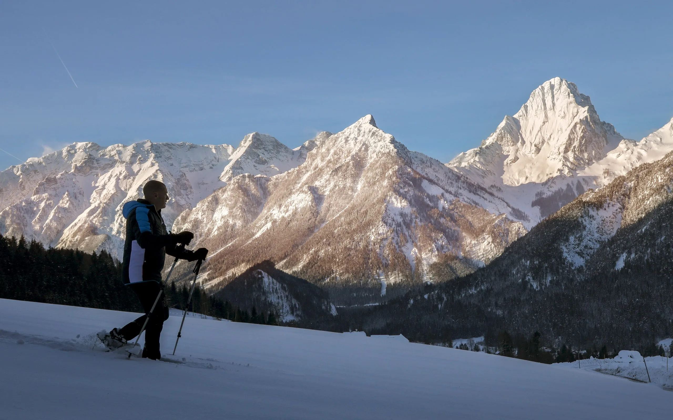 © Johannes Kernmayer Chodec na sněžnicích táhne svou stopu, za ním svítí Priel a Spitzmauer v ranním světle