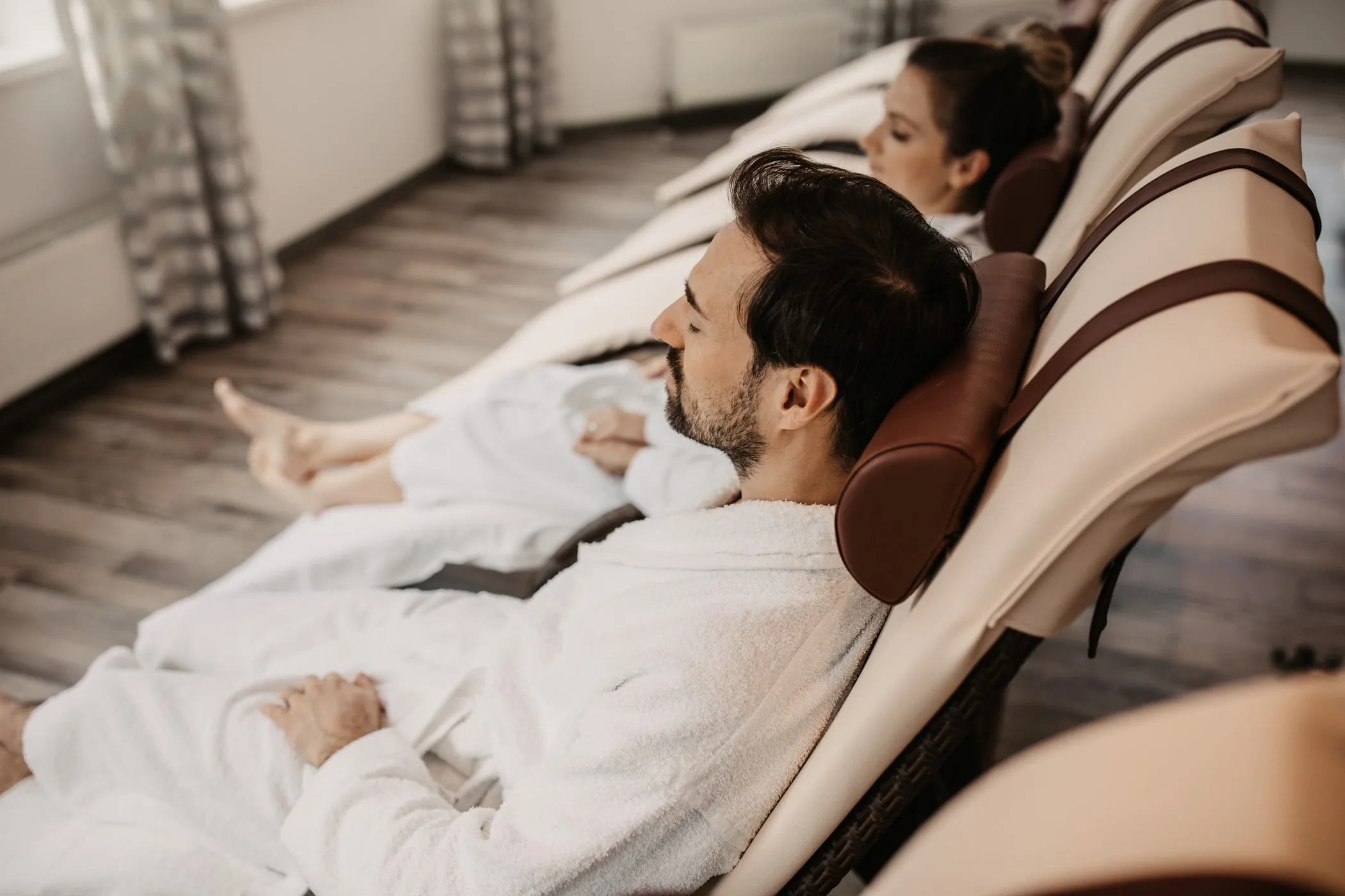 Dva hosté v županech na relaxačních lehátkách v odpočinkové zóně