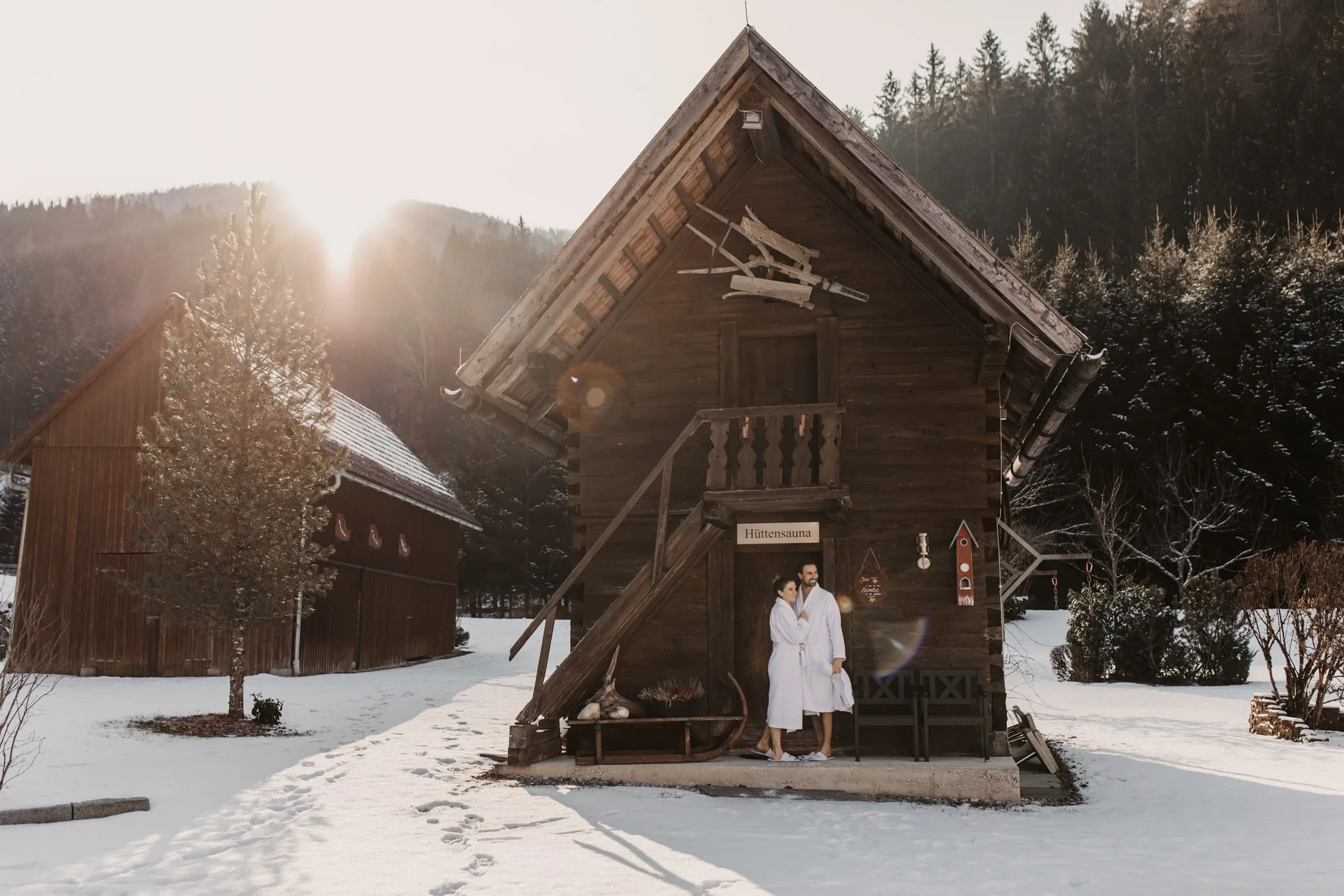 Srubová sauna v protisvětle, všude kolem sníh a les