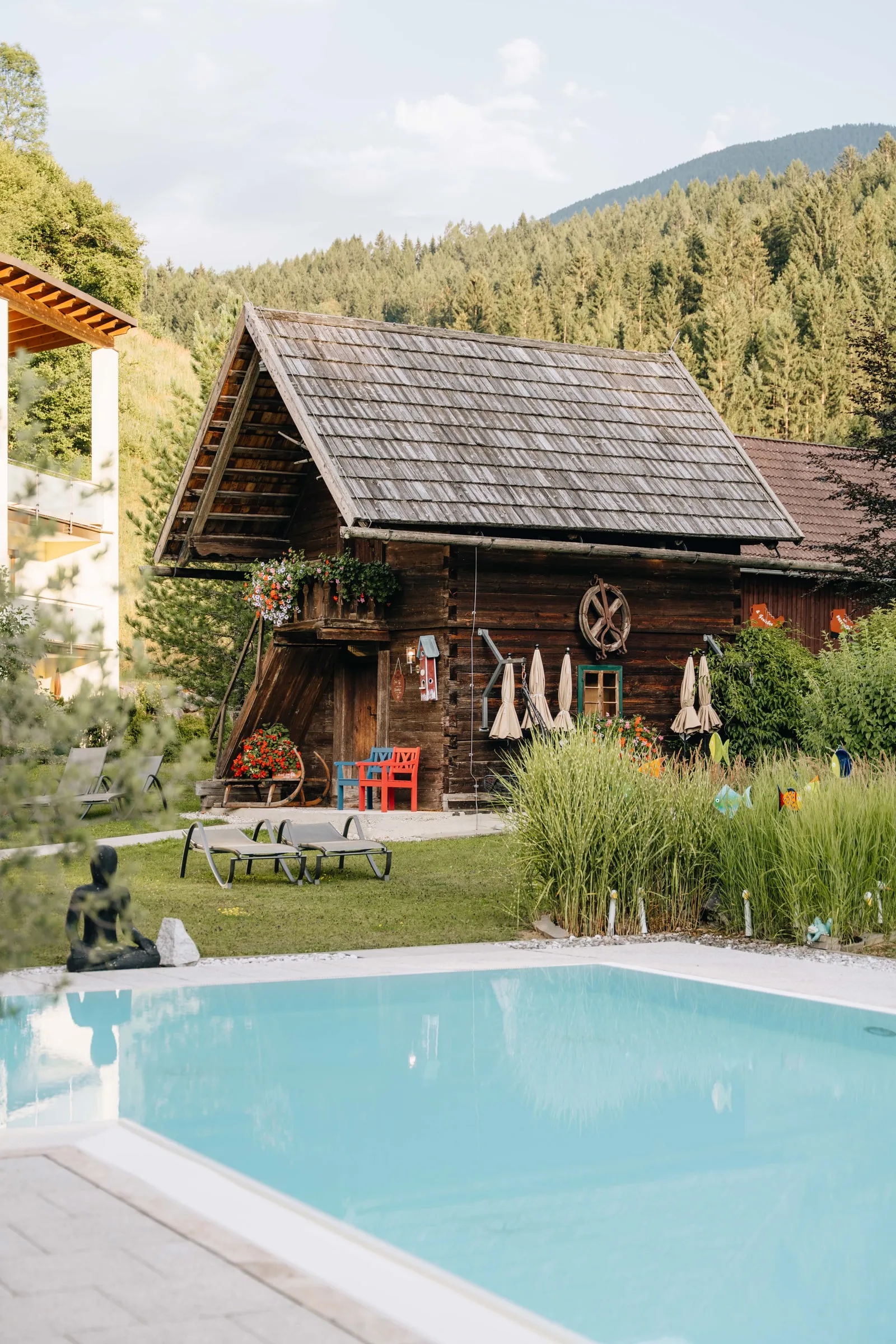 Srubová sauna v zahradě, před ní trávník na lehání a venkovní bazén