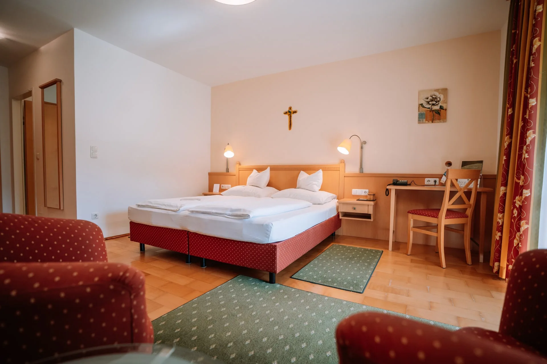 Pokoj Wohlfühlzimmer s červenými křesly před manželskou postelí