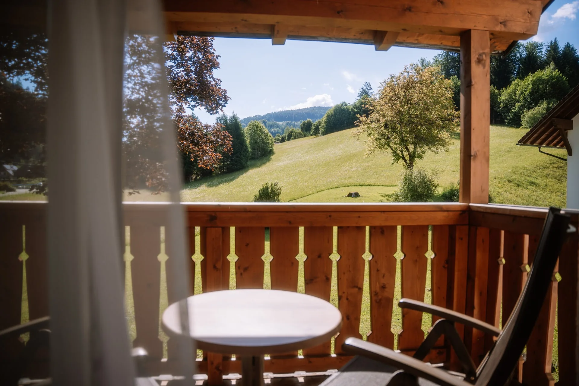 Balkon se stolem a židlí nad loukou