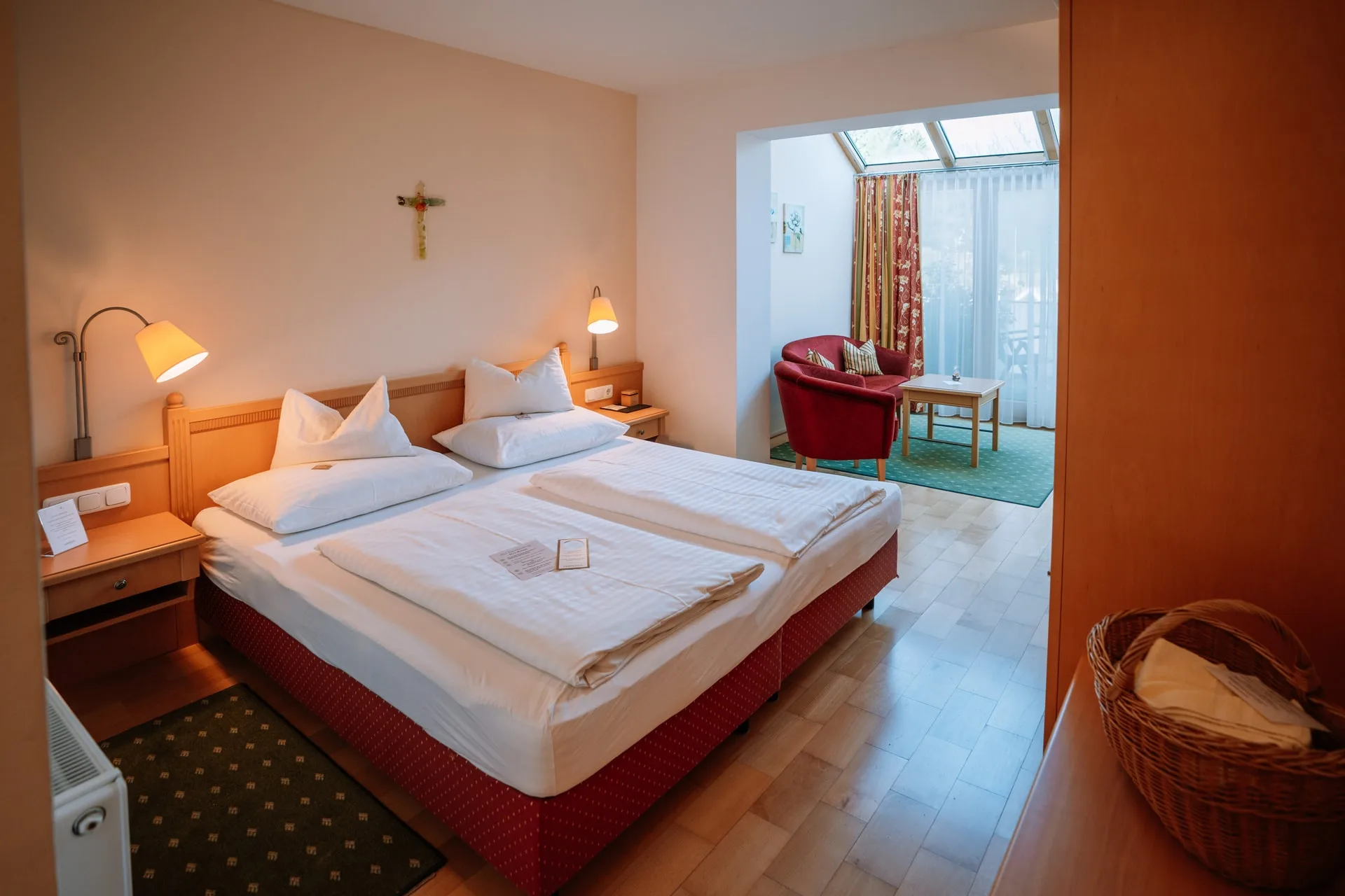 Wohlfühlzimmer mit Doppelbett und hellem Wintergarten mit Sitzecke