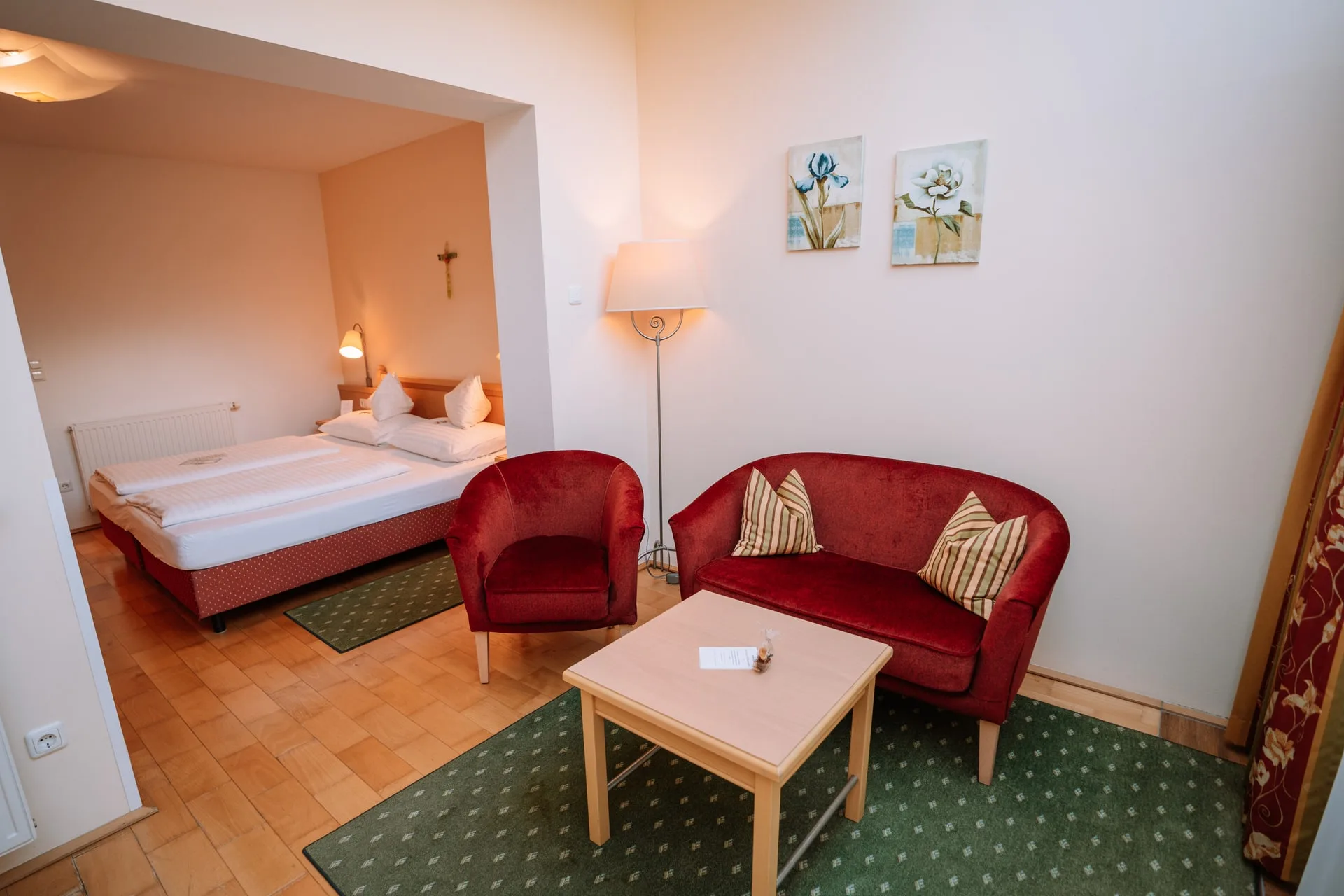 Sitzecke mit rotem Sofa und Sessel vor dem Bett