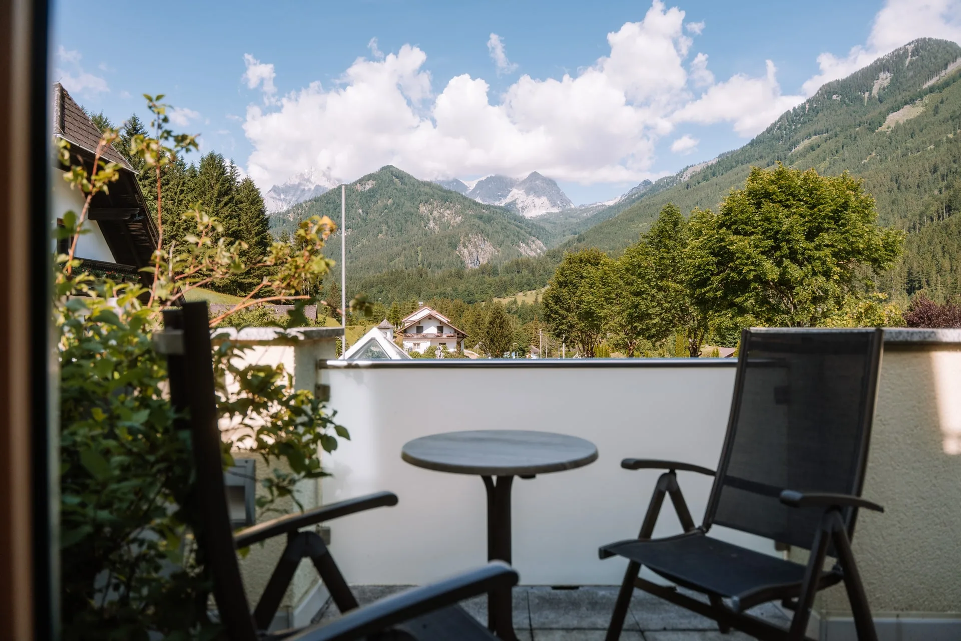 Terrasse mit Tisch und Stühlen, dahinter die Berge